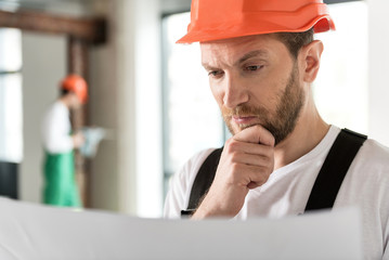 Thoughtful bearded builder looking at draft