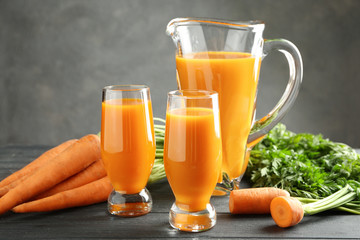 Composition with fresh carrot juice in glassware on table