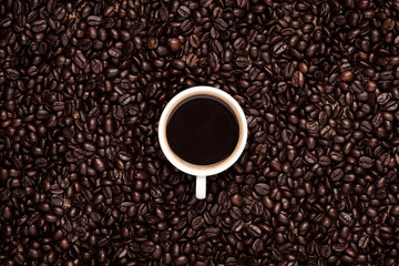 Naklejka premium Coffee cup top view on roasted coffee beans background