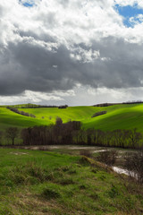 Natural landscape in a spring day, green fields and cloudy sky