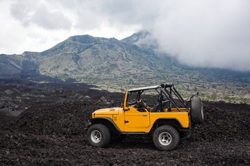 Obraz na płótnie Canvas Offroad yelow vehicle parked at the top of a valley with volcanic rock and mountains in Bali, Indonesia