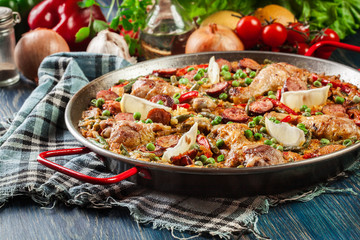 Traditional paella with chicken legs, sausage chorizo and vegetables served in paellera