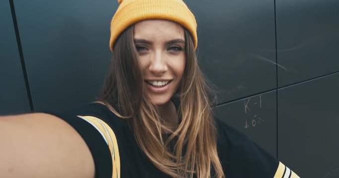 CU Outdoor portrait of young attractive female in stylish outfit making a selfie. Phone camera POV. 4K UHD RAW edited footage