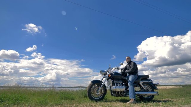 Blue sky and white clouds, a biker and his motorcycle.