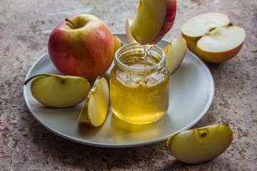 Organic honey in glass jar and red apple on the plate