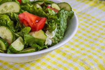 Fresh salad. Tomato, cucumber and greens in white bowl