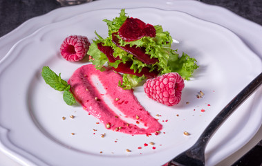 Carpaccio of baked red pray with green salad and raspberry