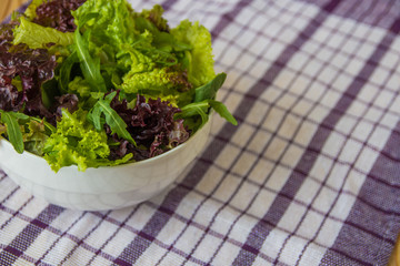 Salad leaves, purple lettuce, spinach, arugula. Mixed fresh salad in a white bowl