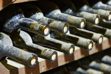 stacked old wine bottles in wine cellar