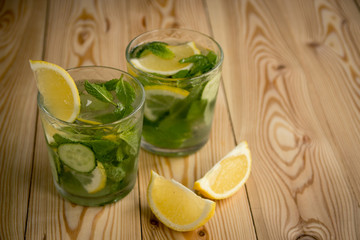 Detox water, fresh organic lemonade with ice, cucumber, lemon and mint on wooden background