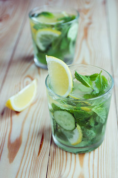 Detox water, fresh organic lemonade with ice, cucumber, lemon and mint on wooden background