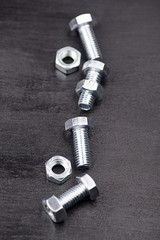 Background of nuts and bolts on black background. Vertical studio shot.