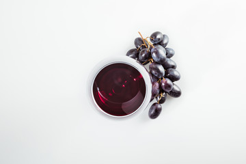 top view of red wine in grass and ripe grapes isolated on white