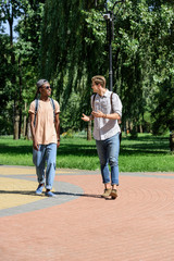 Fototapeta premium multicultural young men having conversation while walking in park