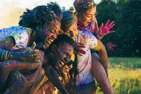 multicultural happy friends piggybacking together at holi festival