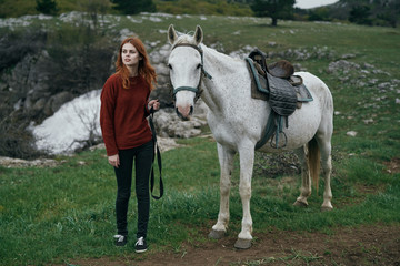Young beautiful woman walking in the mountains with a horse