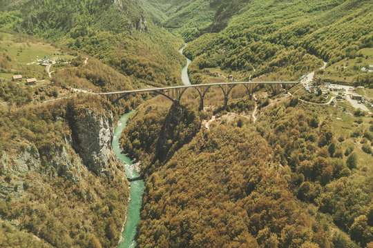 Automobile bridge across the river in the autumn mountains, top view