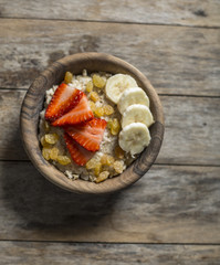 oatmeal porridge with strawberry and banana in wood bowl