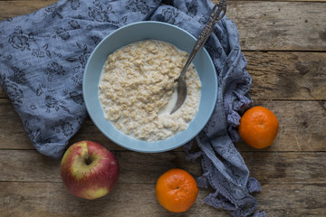 Oatmeal porridge in bowl for breakfast on rustic wooden table