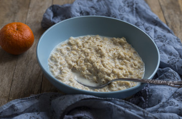 Oatmeal porridge in bowl for breakfast on rustic wooden table