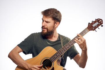 Obraz premium Young guy with a beard on a white isolated background holds a guitar