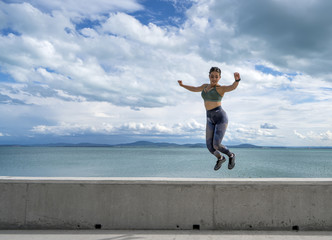 beautiful happy young girl jumping on the beach