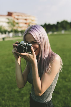 Young woman taking pictures with camera in nature