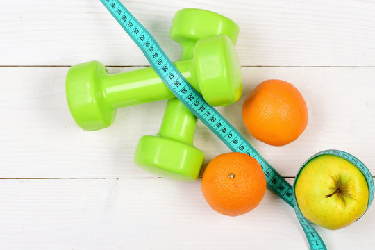 apple, orange with measuring tape, weight dumbbells for diet concept