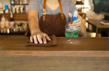 Waitress cleaning the top bar with spray disinfectant