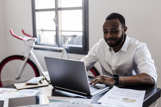 Smiling man using laptop at desk in home office