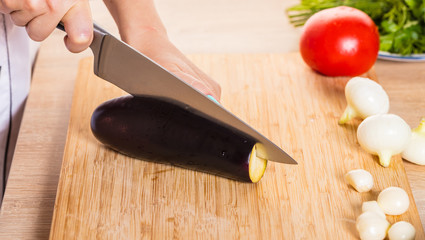 The cook cuts the eggplant