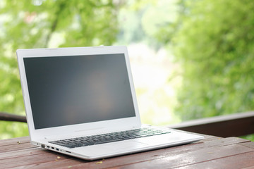 Stock photo :.Computer Laptop on wooden table with blur nature bokeh background, business technology concept