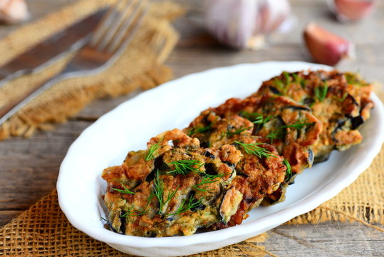 Easy eggplant cutlets. Fried eggplant cutlets with garlic and dill on a white plate and a vintage wooden table. Healthy vegan eggplant recipe. Closeup