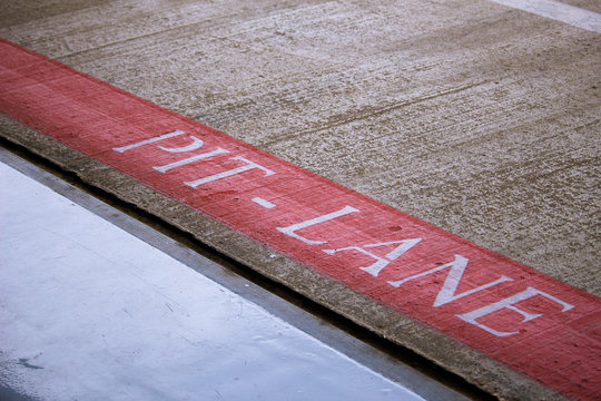 Word Pit Lane panted on the ground at the Silverstone racetrack in the UK. No people, outdoors