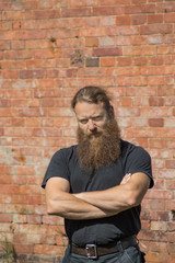 Obraz premium A bearded man with arms crossed on his chest.