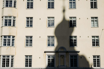 Fototapeta na wymiar the shadow of the Church on the background of houses with Windows