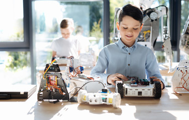Sweet little boy examining front part of robotic vehicle