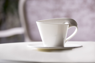 White cup and saucer. On a white table.