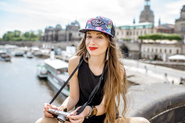 Young woman tourist with photo camera enjoying great view from the bridge on the old town of Dresden in Germany