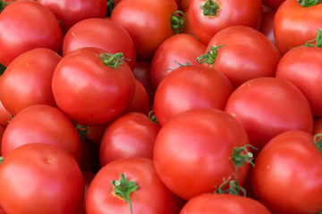 Delicious red tomatoes. A pile of tomatoes. Summer tray market agriculture farm full of organic tomatoes. Fresh tomatoes. It can be used as background