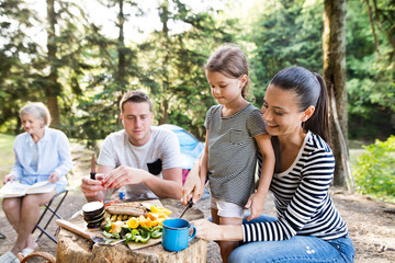 Beautiful family camping in forest, eating together.