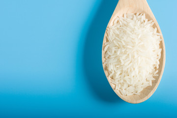 Raw Rice on Wood Spoon in blue background