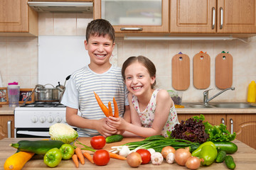 Child girl and boy having fun with tomatoes and carrot. Home kitchen interior with fruits and vegetables. Healthy food concept