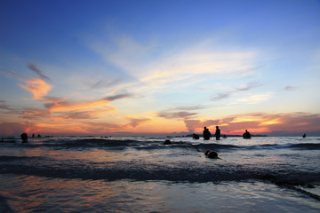 People in the sea, the sunset making two color blue and orange  sky.