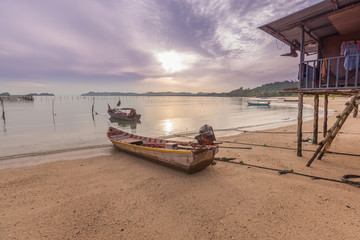 wooden boat and wooden house by the beach during sunrise