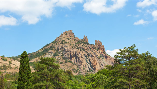 The mountain towering above the forest and the crowns of trees. The mountain range of Karagach, Crimea peninsula