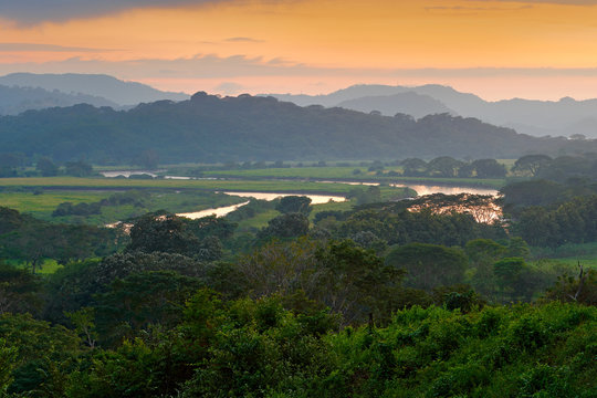 Fototapeta Rio Tarcoles, Carara National Park, Costa Rica. Sunset in beautiful tropic forest landscape. Meander of river Tarcoles. Hills with orange evening sky. Holiday in Costarica. Travel in Central America.