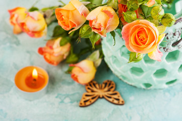 Obraz na płótnie Canvas Fresh orange roses flowers in mint vase and lit candle