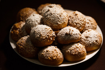 ruddy delicious muffins dusted with powdered sugar on the plate on brown tablecloth