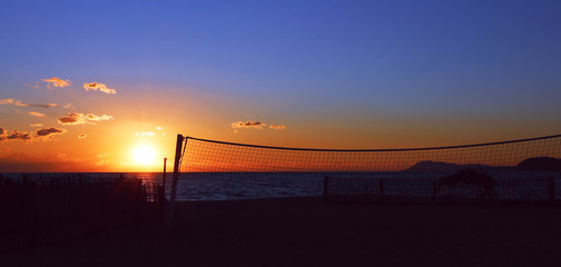 sunset at the beach with volley-ball net against the light